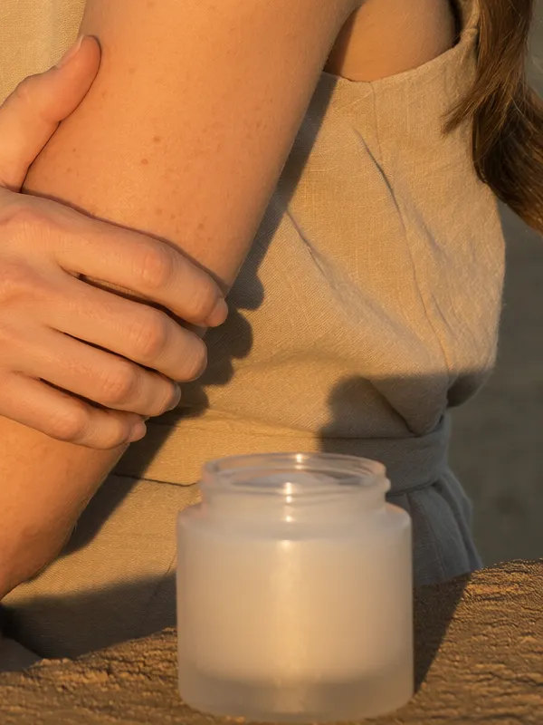 An unbranded frosted skincare jar on warm sandstone at golden hour.